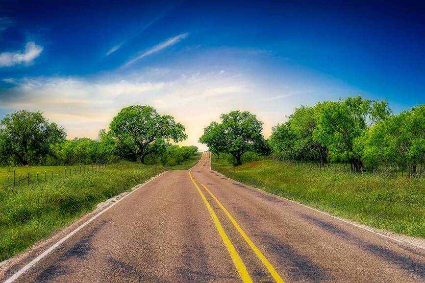 A quiet back road winding through Texas Hill Country juniper country