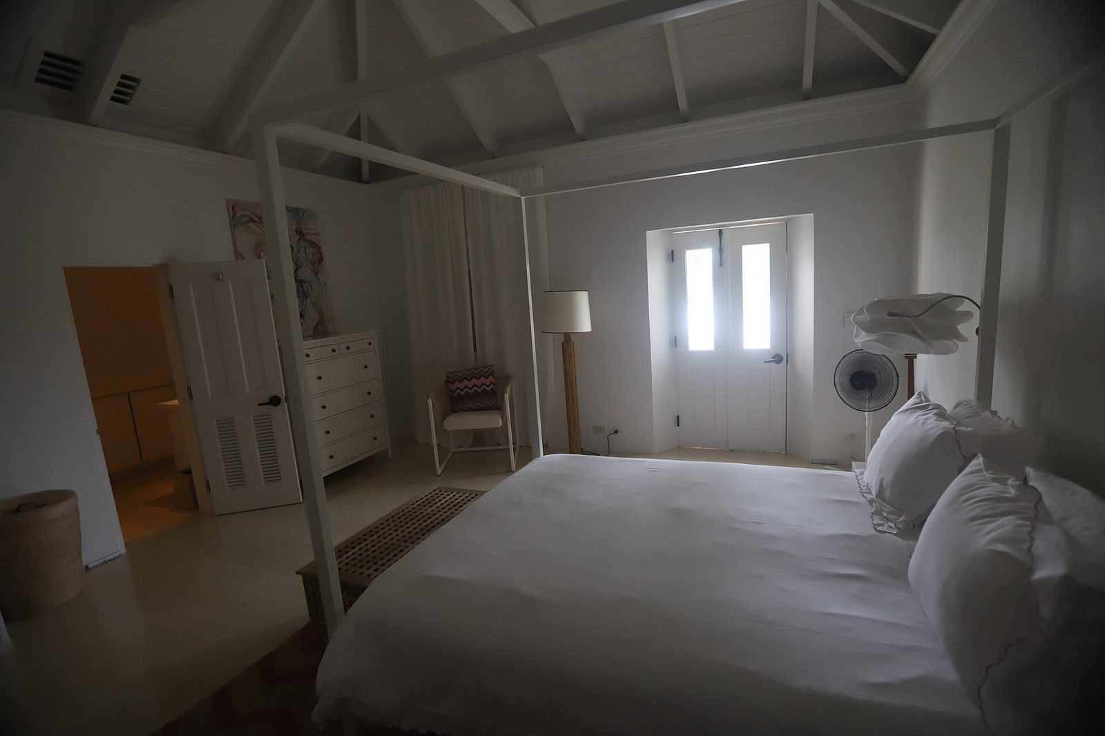 A bright white bedroom with a neatly made bed